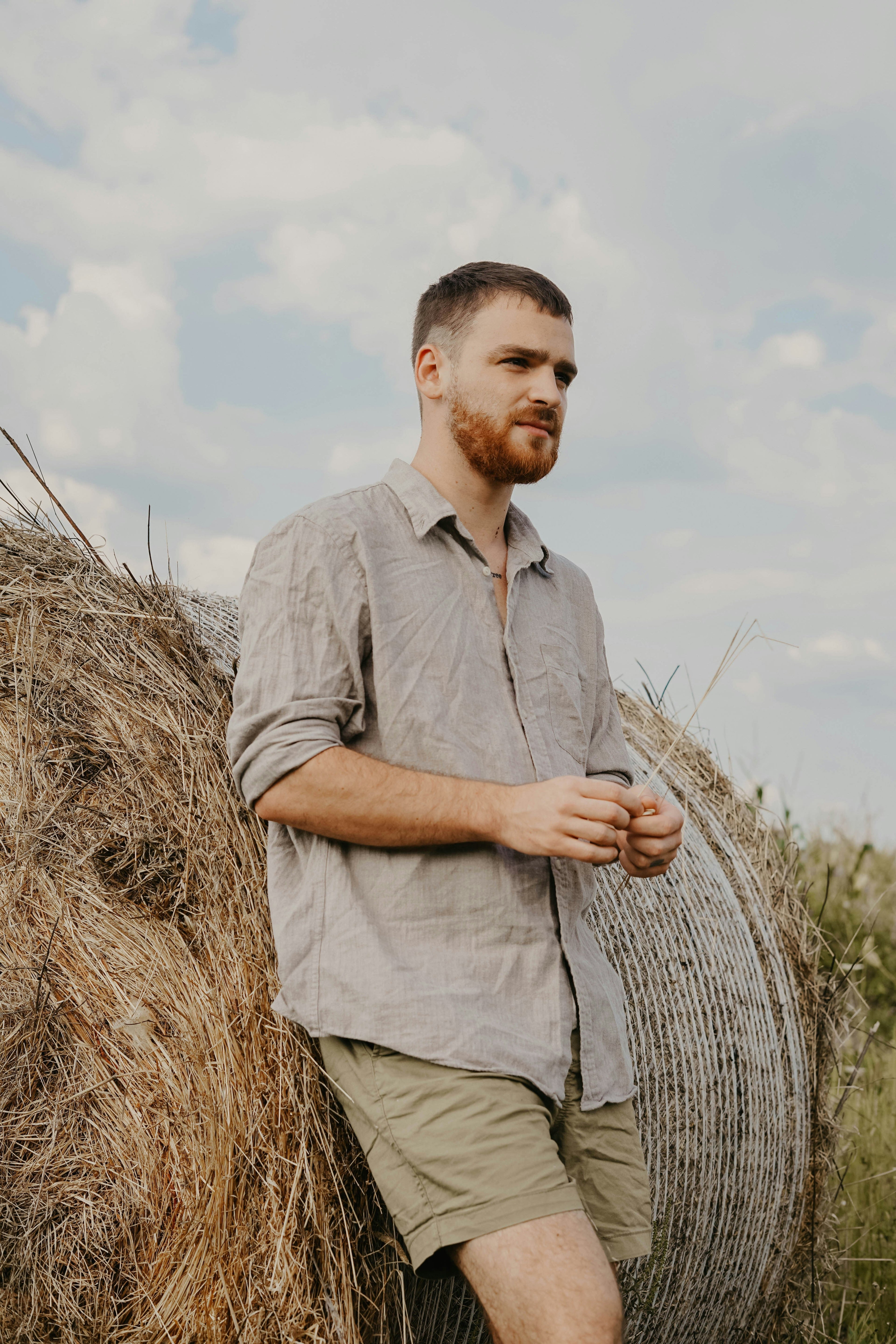 Man leaning against hay bale in linen shirt