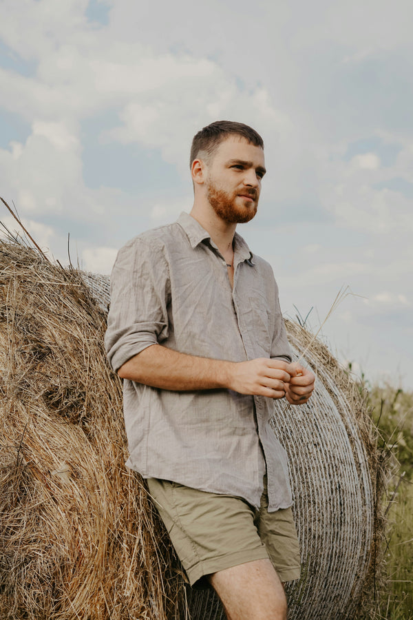 Man leaning against hay bale in linen shirt